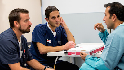 Amro and Chris, members of the Cook Surgery team, talk to a surgeon.