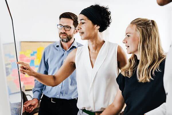 Three people collaborating and interacting with a screen.