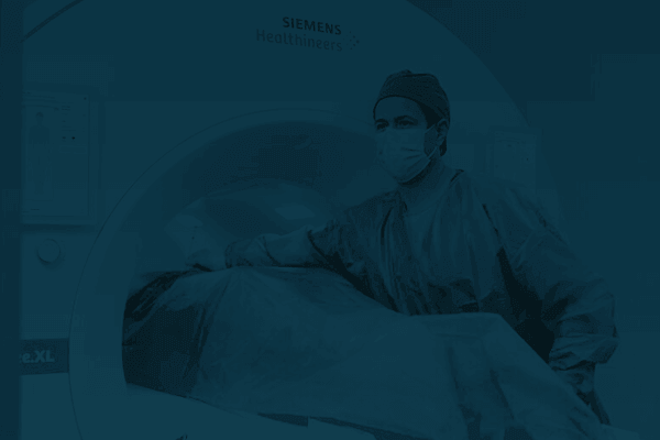 A technician assisting a patient lying down on a stretcher in an MRI machine.