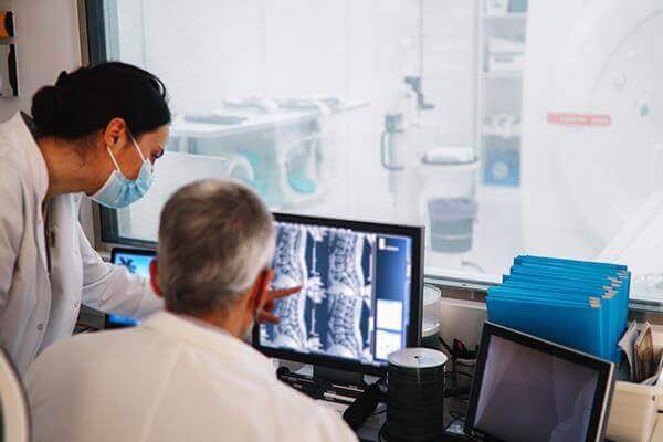Two doctors reviewing scan results on a computer monitor.
