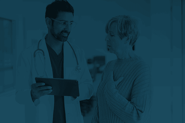 A doctor showing test results to a patient on a tablet.