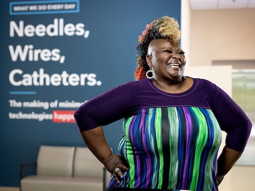 Cook Medical employee poses in front of inspirational signage at headquarters
